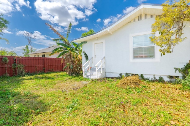 5261 3rd St, Orlando, FL 32810 - view of home's exterior with fence, stucco siding, a yard, and entry steps