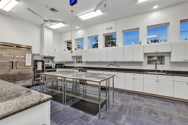 5305 Indian Ocean Loop, Tavares, FL 32778 - kitchen with a sink, a high ceiling, white cabinetry, recessed lighting, and dark stone counters