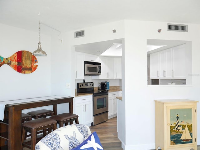 kitchen featuring visible vents, white cabinetry, appliances with stainless steel finishes, and wood finished floors
