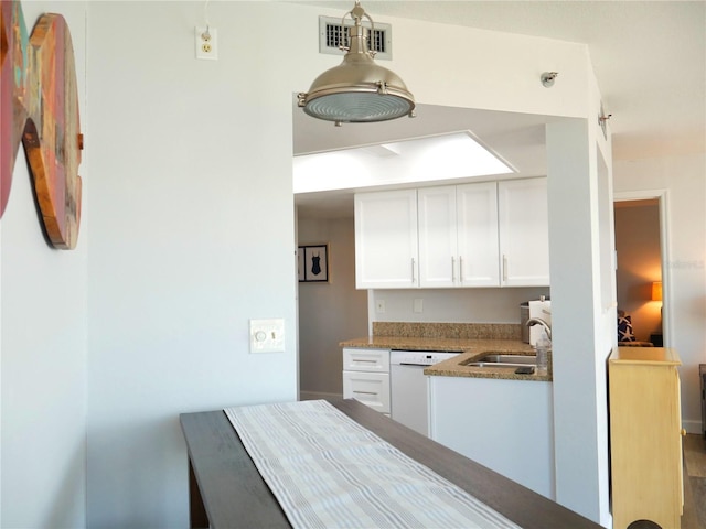 kitchen featuring visible vents, dishwasher, a sink, stone countertops, and white cabinetry