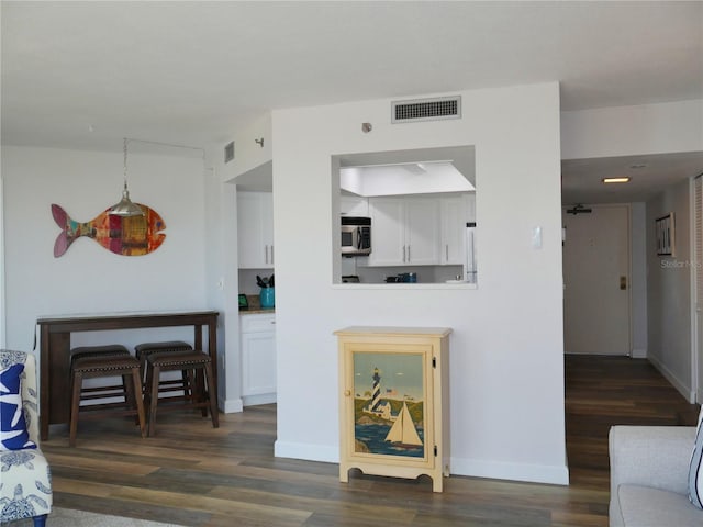 living area featuring visible vents, baseboards, and wood finished floors