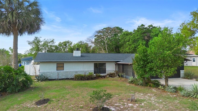 ranch-style home featuring a front lawn, stucco siding, and fence