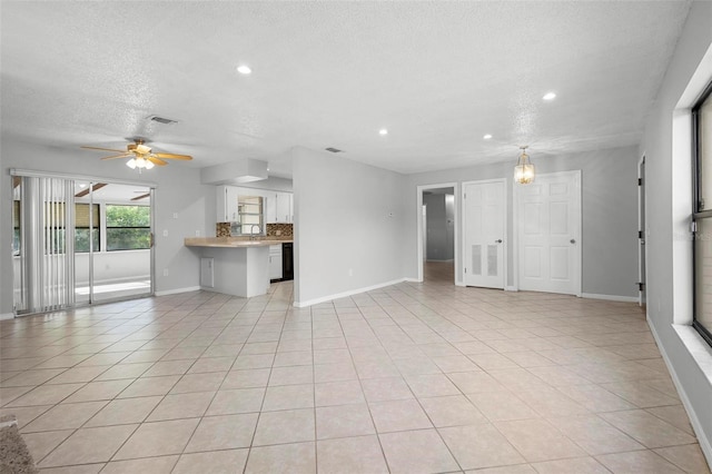 unfurnished living room featuring a textured ceiling, a sink, baseboards, visible vents, and a ceiling fan