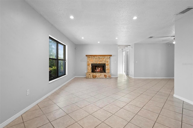 unfurnished living room with a stone fireplace, a textured ceiling, visible vents, and recessed lighting