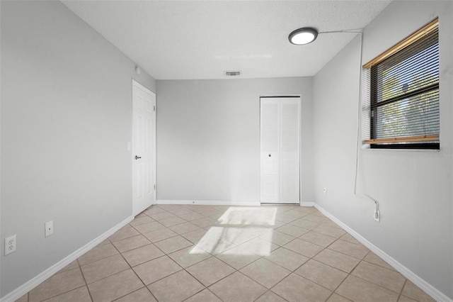 unfurnished room featuring baseboards, visible vents, and light tile patterned floors