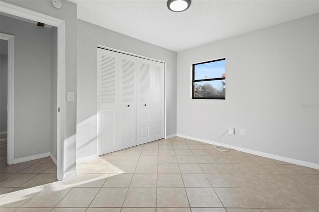 unfurnished bedroom with a closet, baseboards, and light tile patterned floors