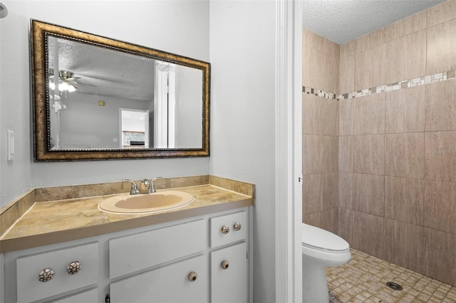full bath featuring toilet, vanity, a textured ceiling, and tiled shower