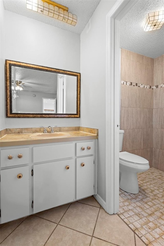 bathroom with tile patterned flooring, vanity, a textured ceiling, and toilet