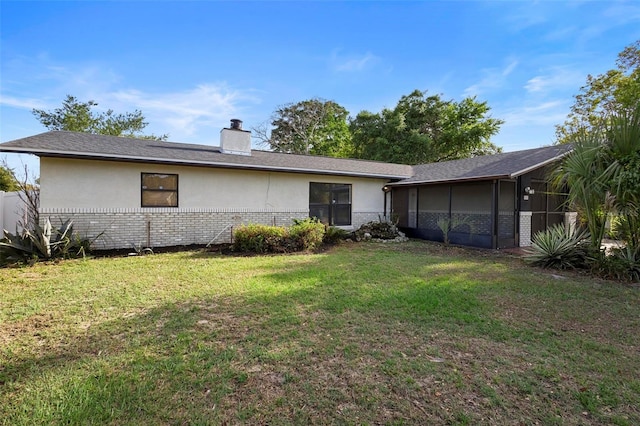 rear view of house with fence, brick siding, a yard, and stucco siding