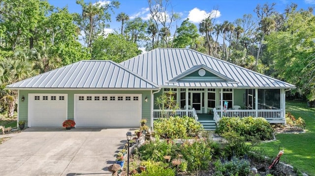 view of front of home featuring covered porch, metal roof, a garage, concrete driveway, and a standing seam roof