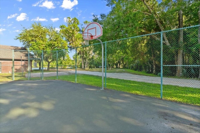 view of basketball court featuring community basketball court, a yard, fence, and a gate