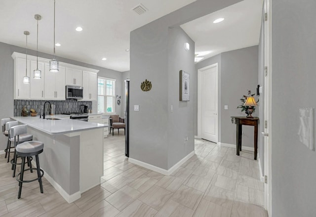 kitchen featuring visible vents, a sink, light countertops, appliances with stainless steel finishes, and a kitchen breakfast bar