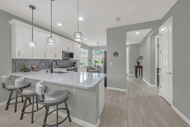 kitchen with tasteful backsplash, visible vents, a sink, light countertops, and appliances with stainless steel finishes