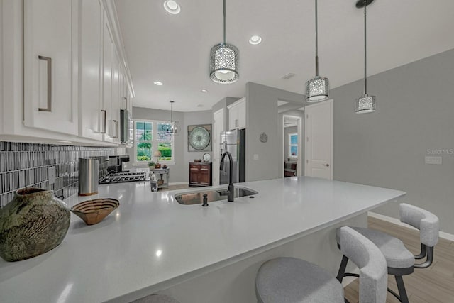kitchen with a peninsula, light countertops, white cabinets, appliances with stainless steel finishes, and a sink