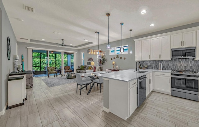 kitchen featuring tasteful backsplash, visible vents, open floor plan, appliances with stainless steel finishes, and a tray ceiling