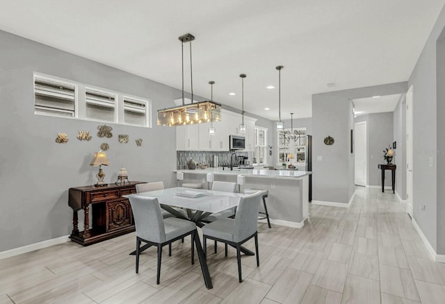 dining space featuring a chandelier, baseboards, and recessed lighting