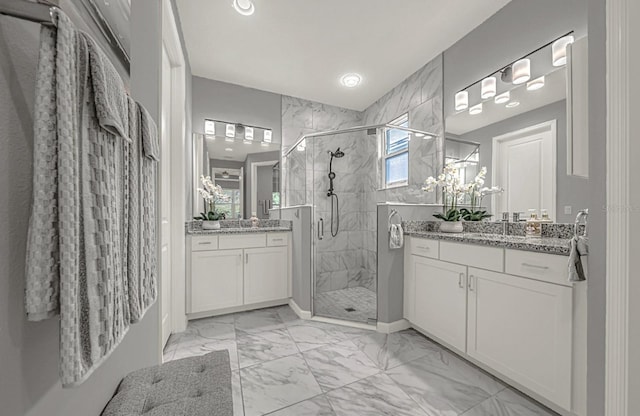 full bath with a sink, two vanities, marble finish floor, and a stall shower