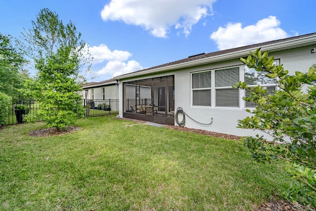 back of property featuring a sunroom, a yard, stucco siding, and fence
