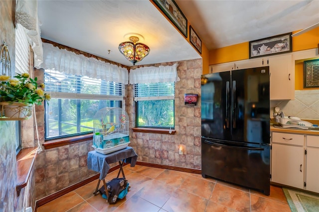 kitchen with white cabinets, freestanding refrigerator, and light tile patterned floors
