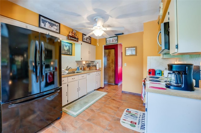kitchen with stainless steel microwave, tasteful backsplash, freestanding refrigerator, white dishwasher, and light countertops