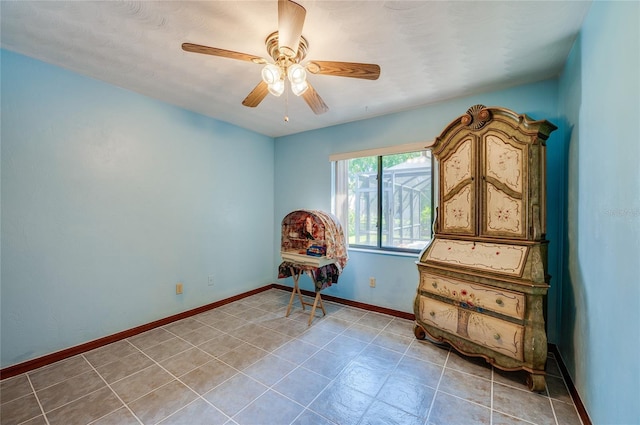 interior space with light tile patterned flooring, baseboards, and ceiling fan