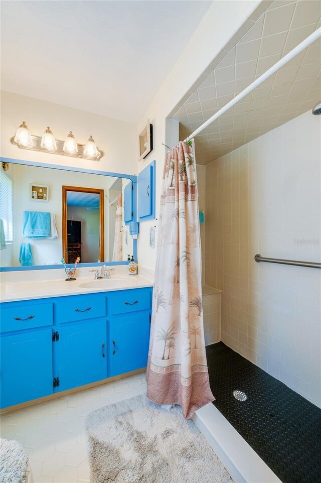 full bathroom with tile patterned floors, vanity, and a tile shower