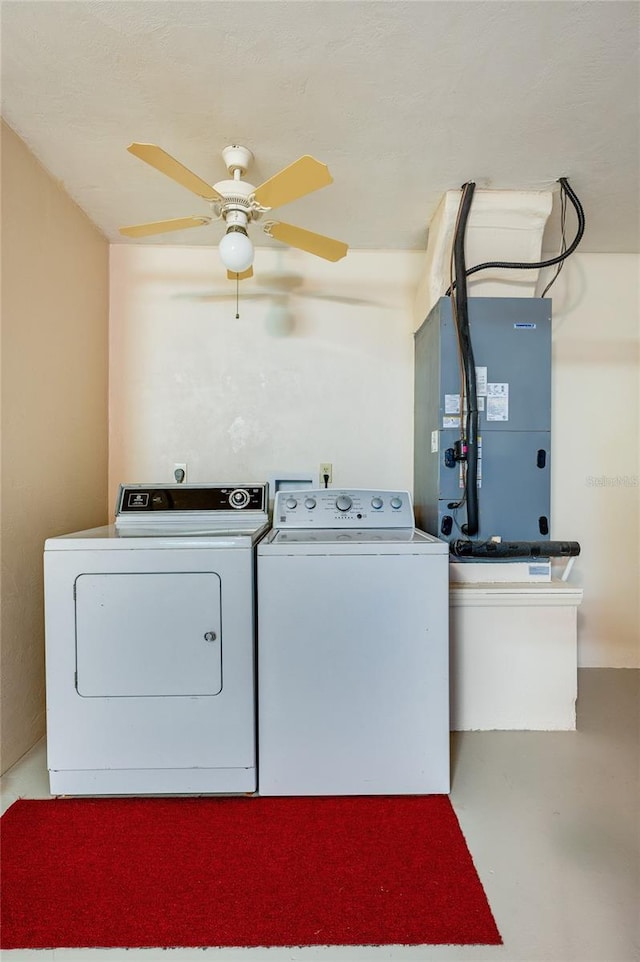 clothes washing area featuring washing machine and dryer, a ceiling fan, heating unit, and laundry area