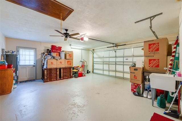 garage with a garage door opener, a ceiling fan, and electric water heater