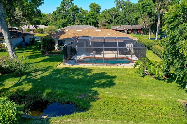 rear view of property featuring glass enclosure, an outdoor pool, a yard, and a patio