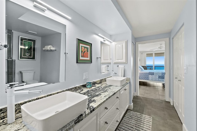 ensuite bathroom featuring toilet, connected bathroom, double vanity, and a sink