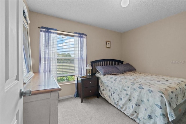 bedroom featuring baseboards, a textured ceiling, and light carpet