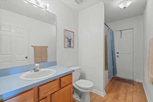 full bath with visible vents, wood finished floors, vanity, toilet, and shower / tub combo with curtain