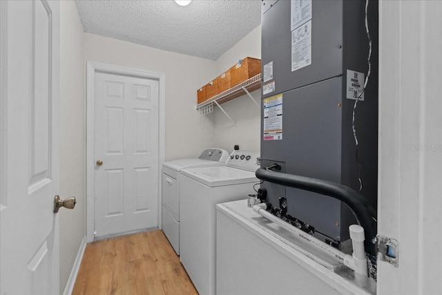 laundry room featuring independent washer and dryer, laundry area, a textured ceiling, light wood-style flooring, and heating unit
