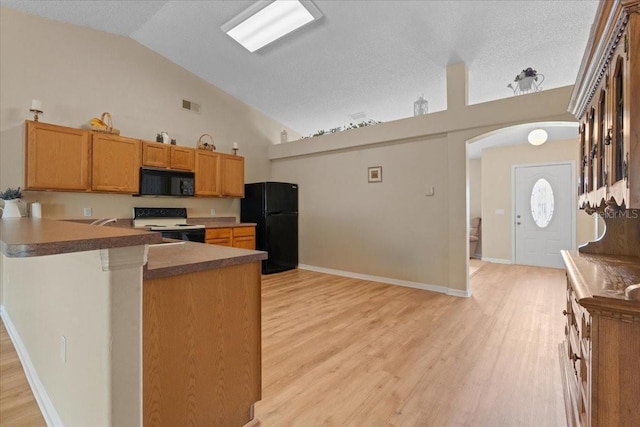 kitchen with light wood-style floors, arched walkways, vaulted ceiling, visible vents, and black appliances
