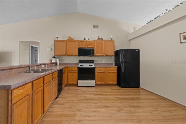 kitchen featuring a sink, visible vents, a peninsula, vaulted ceiling, and black appliances