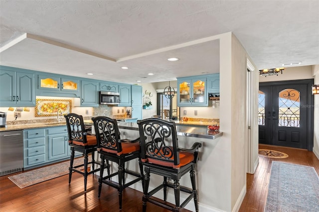 761 Marina Point Dr Unit 7610, Daytona Beach, FL 32114 - kitchen featuring glass insert cabinets, a kitchen bar, blue cabinetry, appliances with stainless steel finishes, and dark wood-style floors