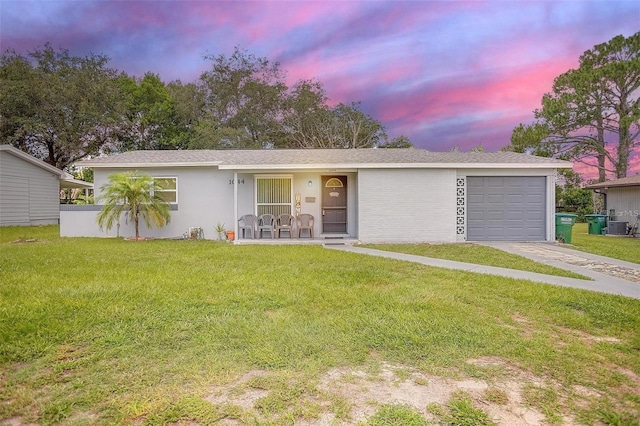 single story home with concrete driveway, stucco siding, an attached garage, central AC, and a yard