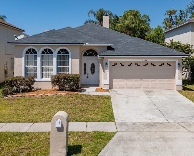 ranch-style home featuring concrete driveway, stucco siding, a chimney, a front yard, and a garage
