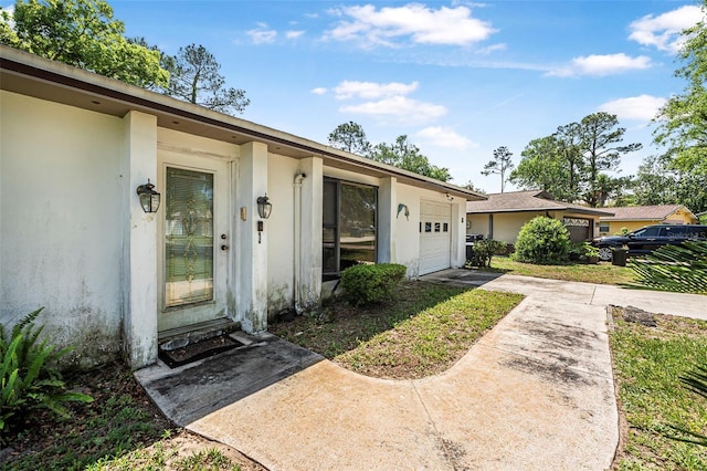 8 Faith Ln, Palm Coast, FL 32137 - view of exterior entry with an attached garage, concrete driveway, and stucco siding