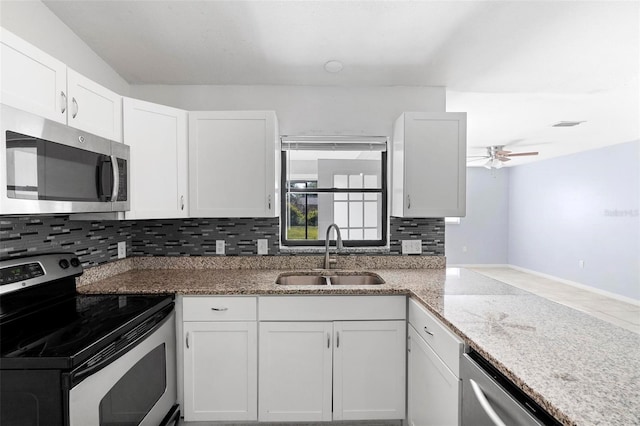 kitchen featuring white cabinetry, backsplash, light stone countertops, appliances with stainless steel finishes, and a sink