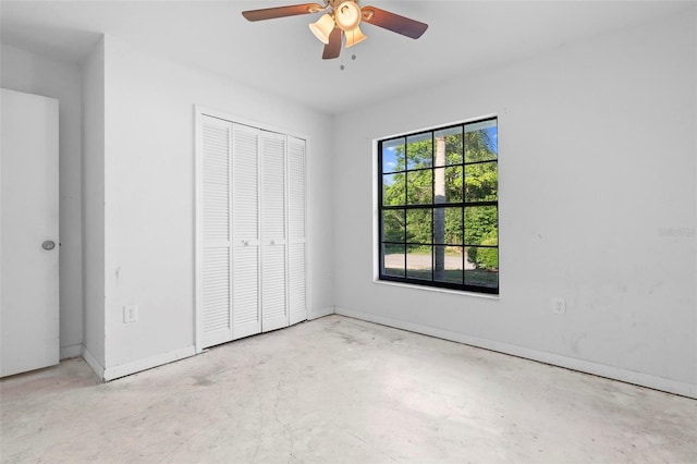 unfurnished bedroom with unfinished concrete floors, a closet, baseboards, and ceiling fan