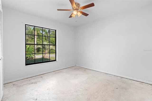 spare room featuring unfinished concrete flooring, baseboards, and ceiling fan