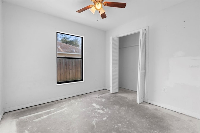 unfurnished bedroom with concrete flooring, a closet, baseboards, and a ceiling fan