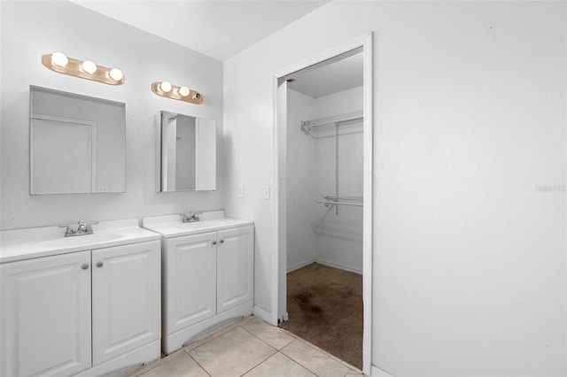 bathroom featuring a sink, tile patterned floors, two vanities, and a walk in closet
