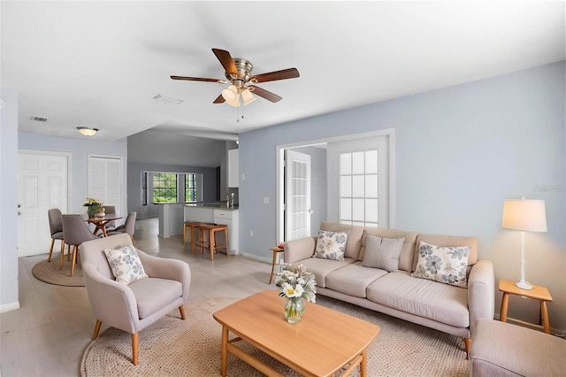 living room with visible vents, baseboards, and a ceiling fan