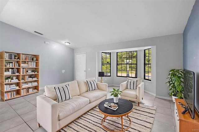living room featuring visible vents, baseboards, vaulted ceiling, and light tile patterned flooring