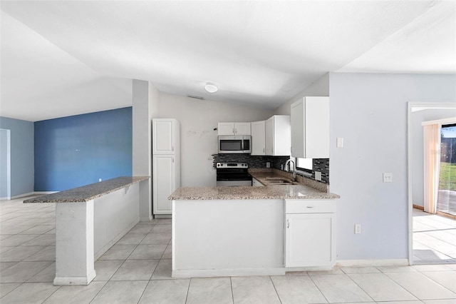 kitchen with a peninsula, white cabinetry, backsplash, appliances with stainless steel finishes, and a sink