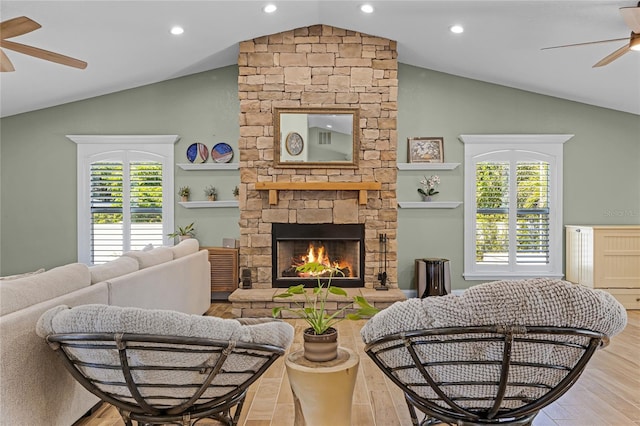 living area with a healthy amount of sunlight, a fireplace, a ceiling fan, and vaulted ceiling