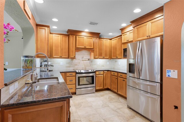 kitchen featuring visible vents, a sink, appliances with stainless steel finishes, dark stone counters, and backsplash