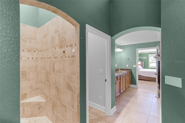 bathroom with a textured wall, crown molding, ensuite bath, vanity, and tile patterned floors